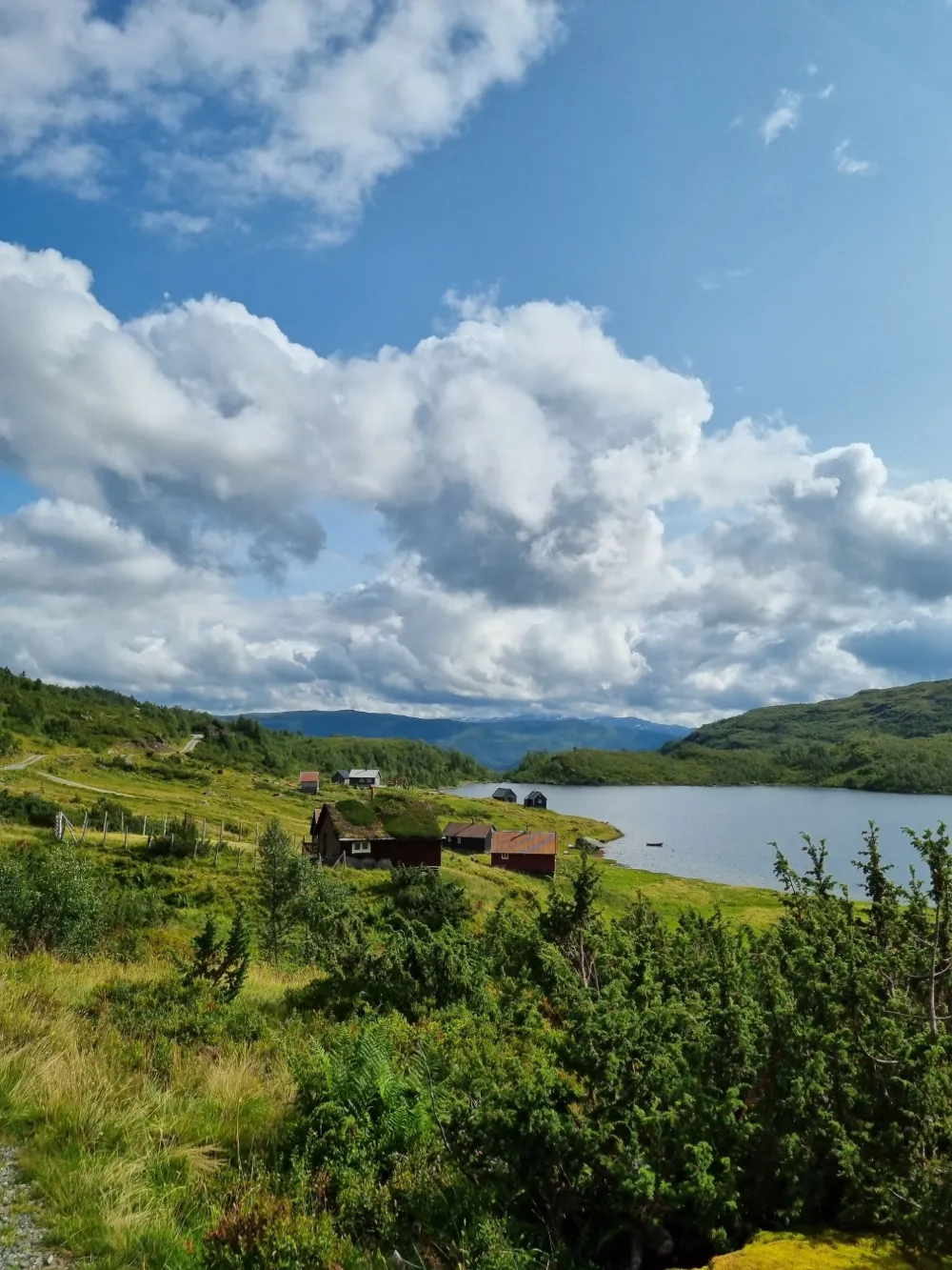 Turvekattoisia mökkejä vuoristojärven rannalla