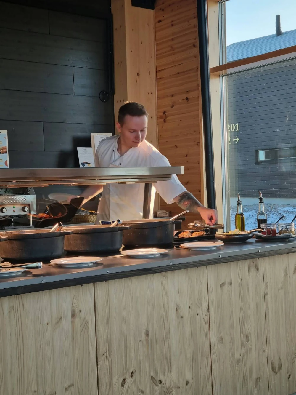 Maidu kokintakissa hotellin buffetpöydän ääressä, ikkunan takana lunta